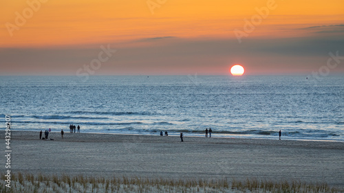 Sunset on the beach, Orange sky blue water silhouets on the strand shore sand
 photo