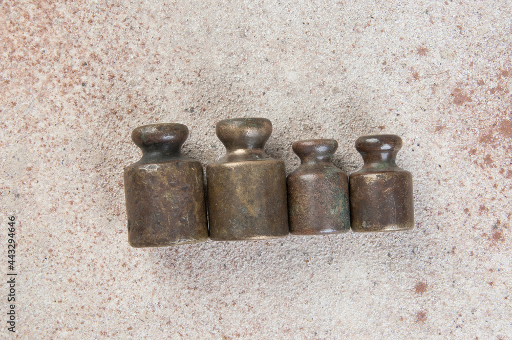 Four antique bronze weights for scales on concrete background. Four antique bronze weights for scales on concrete background.