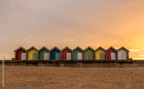 The vibrant and colorful beach huts by the promenade overlooking Blyth beach with a lovely sunset in Northumberland, England