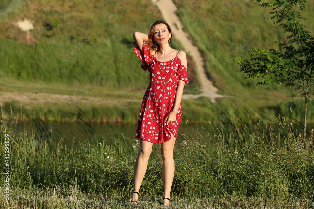 Slender woman in summer dress standing near the lake Slender woman in summer dress standing near the lake