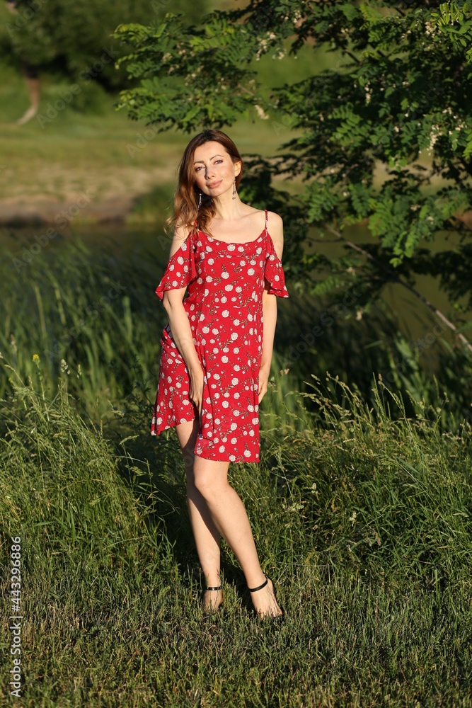 Slender woman in red dress against the grass Slender woman in red dress against the grass