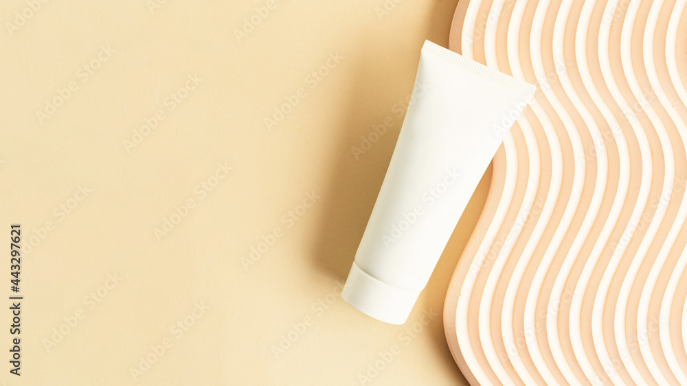 Blank white cosmetics tube on the beige background.Wavy podium near it.Good as cosmetic mockup,pastel large banner with copy space. Blank white cosmetics tube on the beige background.Wavy podium near it.Good as cosmetic mockup,pastel large banner with copy space.