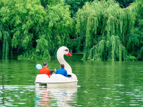 Fototapeta Naklejka Na Ścianę i Meble -  Happy family enjoying a nice day in Alexandru Ioan Cuza Titan park in Bucharest on a pedal boat in shape of a swan