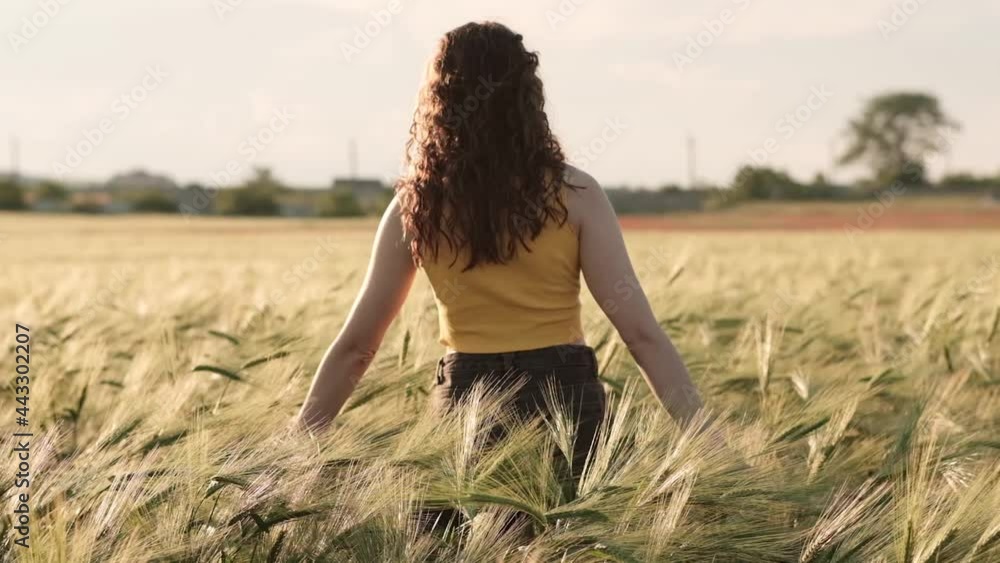 Beautiful carefree woman enjoying nature and sunlight in wheat field at incredible colorful sunset Beautiful carefree woman enjoying nature and sunlight in wheat field at incredible colorful sunset