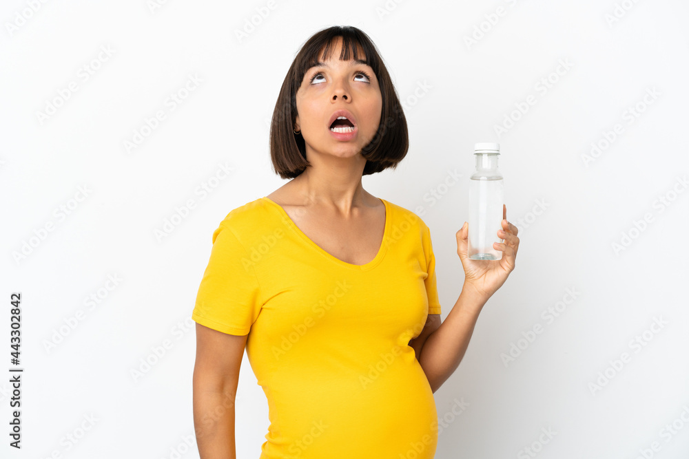 Young pregnant woman holding a bottle of water isolated on white background looking up and with surprised expression Young pregnant woman holding a bottle of water isolated on white background looking up and with surprised expression