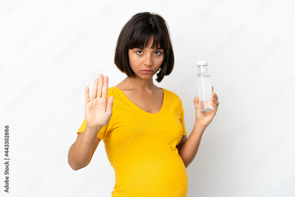 Young pregnant woman holding a bottle of water isolated on white background making stop gesture Young pregnant woman holding a bottle of water isolated on white background making stop gesture