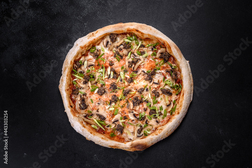 Fresh delicious Italian pizza with meat, mushrooms and tomatoes on a dark concrete background