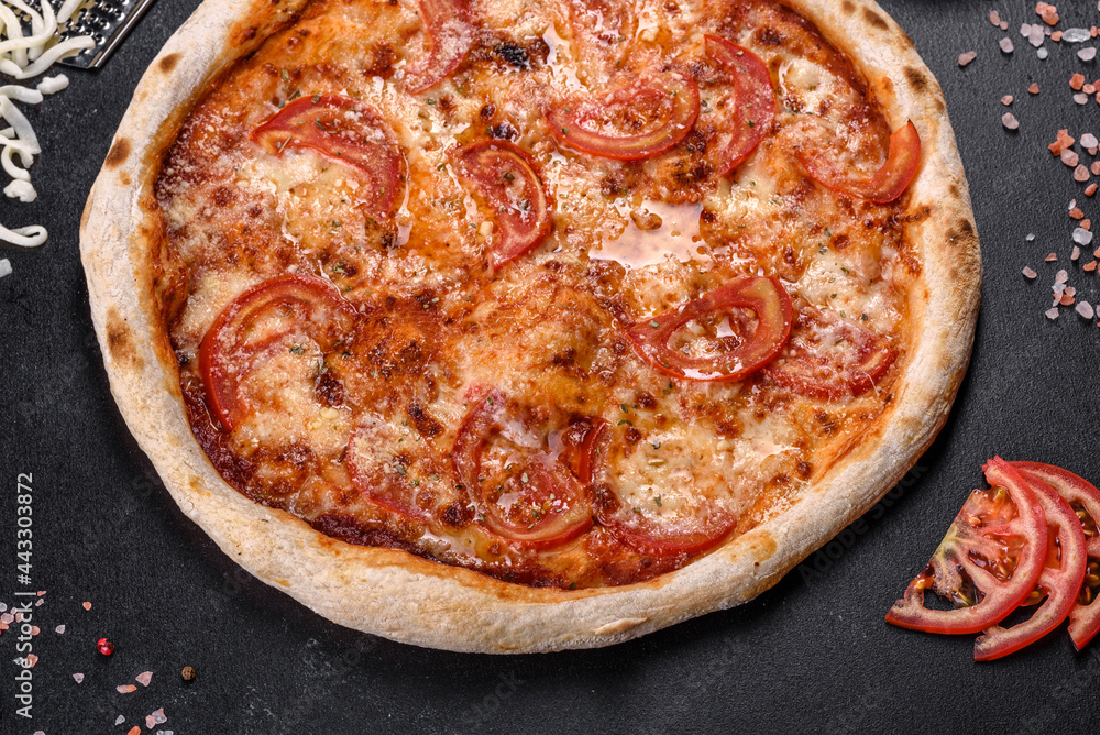 Fresh delicious Italian pizza with mushrooms and tomatoes on a dark concrete background