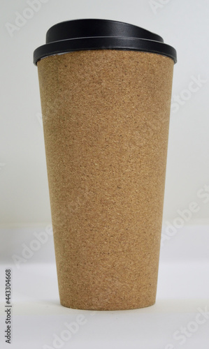 textured decorative light brown glass for hot drinks with a black plastic lid on a white background