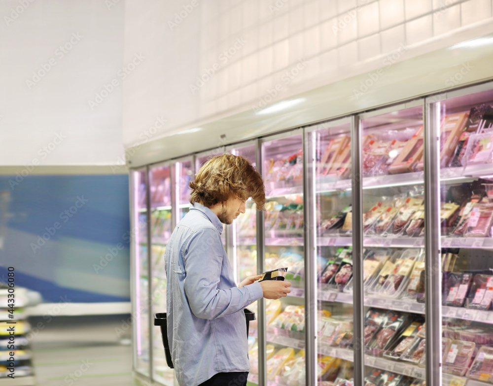  Men choosing frozen food from a supermarket freezer.