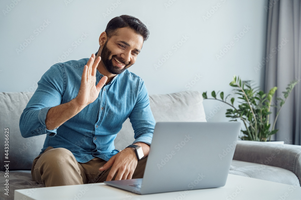 Indian business man waving hand to online client using laptop computer Indian business man waving hand to online client using laptop computer