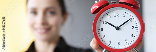 Closeup of red alarm clock in hands of young woman