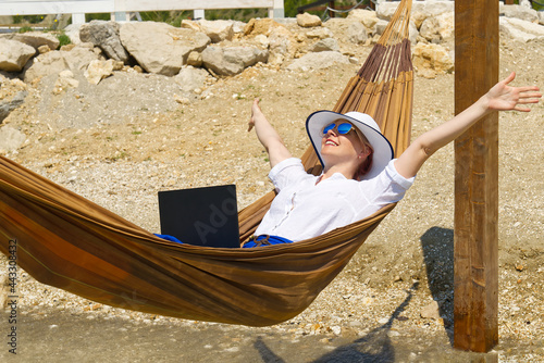 Work from anywhere. Young smilyng woman  female freelancer in straw hat working on laptop on beach. freelancer paradise  Dream work  freedom of teleworking. distance work concept. freelance job at