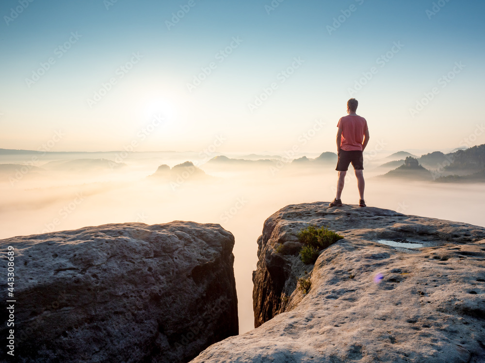 Tourist  or hiker on the peak of high rocks watching morning mist
