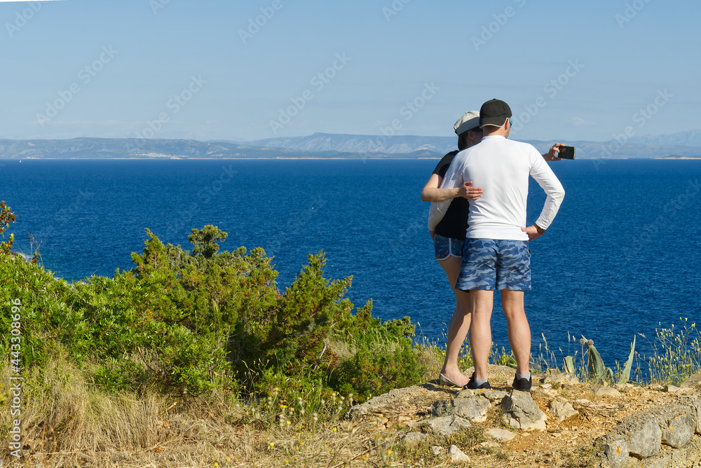 friends looking on a cliff above the sea, hikers looking at view and enjoying enjoy climbing to the top. Active lifestyle.