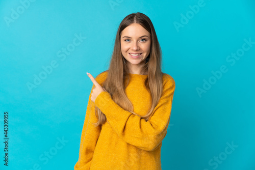 Young Lithuanian woman isolated on blue background pointing to the side to present a product