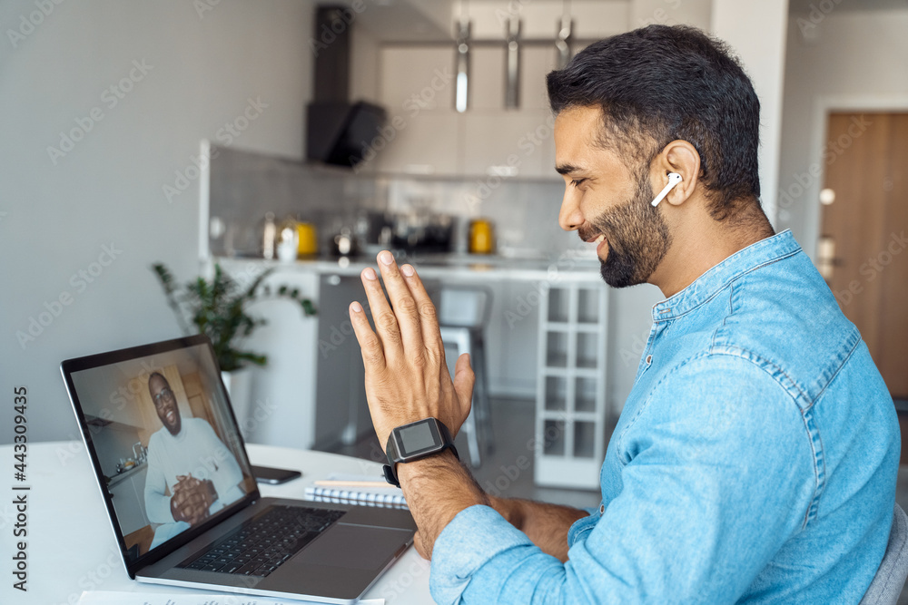 © Stock 4 You - Mature eastern Indian man sitting at home desk front of laptop greeting business partner on screen. 40s freelance entrepreneur businessman communicate remotely online with colleague using pc computer