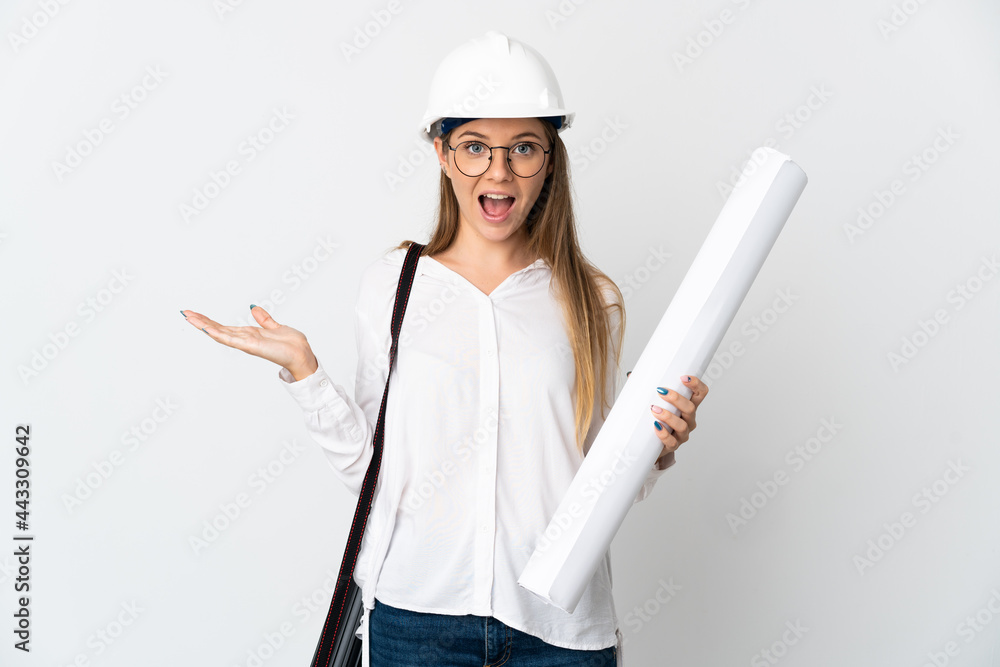 Young Lithuanian architect woman with helmet and holding blueprints isolated on white background with shocked facial expression Young Lithuanian architect woman with helmet and holding blueprints isolated on white background with shocked facial expression
