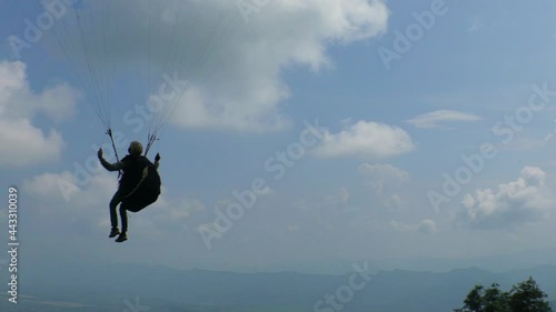 silhouette of a person jumping on the sky - paraglider take off