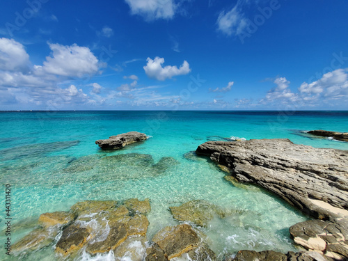 Crystal clear water amidst rocks and sandy beaches of North Bimini's west coast in Bahamas.