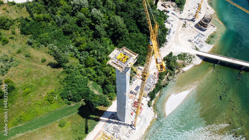 Aerial drone view of tower crane and scaffolding at construction site. Building concrete pillar for highway. A new concrete bridge under construction. 
