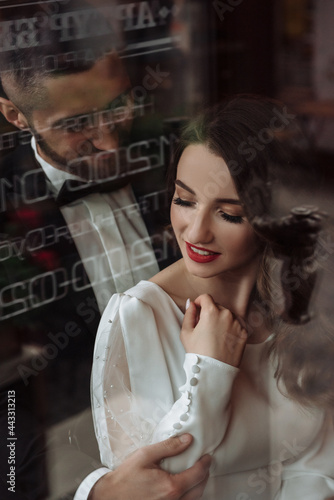 Close portrait of the bride and groom through the window glass © Nadiia