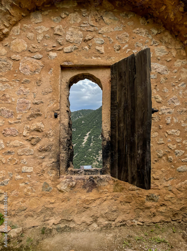 lookout in medieval stone wall and wooden shutter