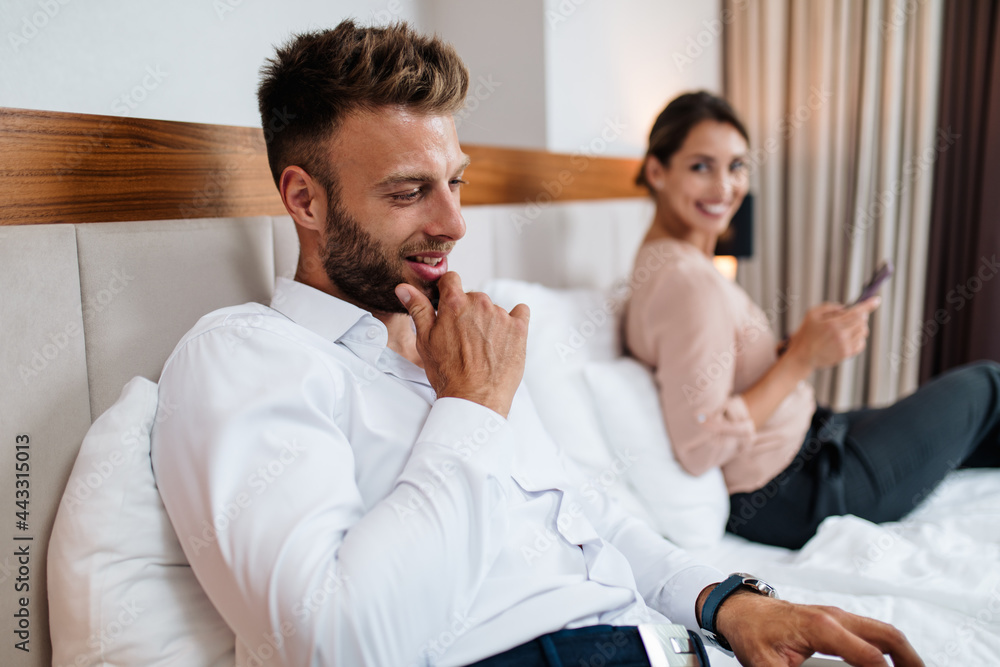 Young attractive business couple using laptop and mobile phone in hotel room Young attractive business couple using laptop and mobile phone in hotel room