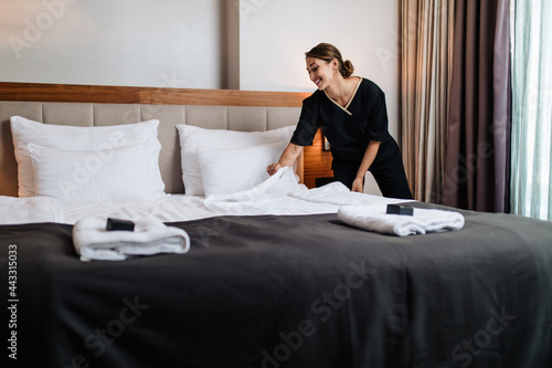 Photos Attractive young maid tidying the hotel room.