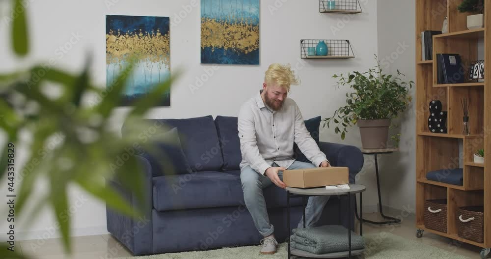 Happy man unpacking parcel at home Happy man unpacking parcel at home