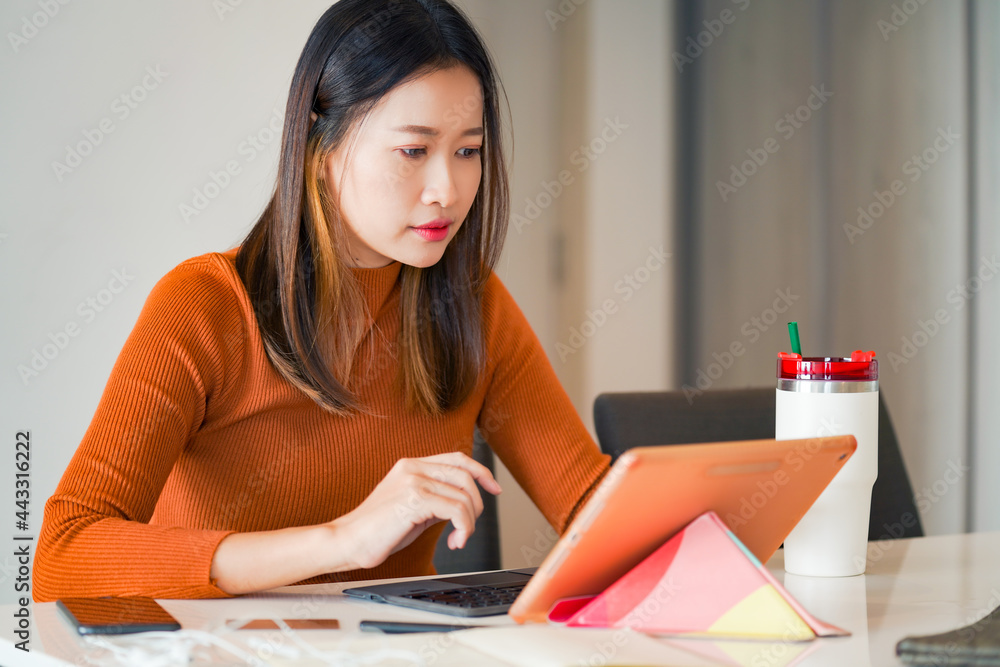Asian woman use tablet with internet for online small business work on table in apartment. Female freelance type and scratch on tablet touch screen for working business job or online shopping at home. Asian woman use tablet with internet for online small business work on table in apartment. Female freelance type and scratch on tablet touch screen for working business job or online shopping at home.