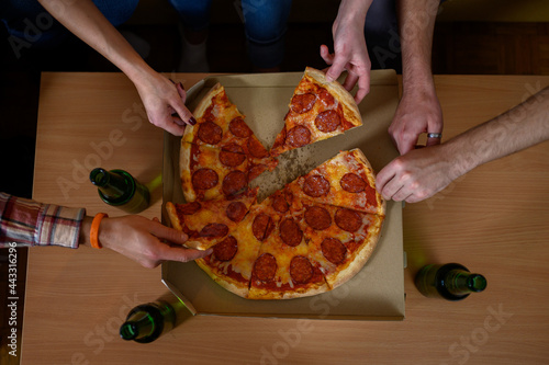 Unrecognizable people's hands each grabbing a slice of pizza