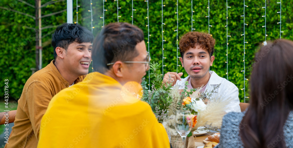 Group of diversity Asian millennial people friends enjoy outdoor garden dinner party eating food and drinking wine with talking together. Reunion friendship meeting celebration and night life concept.
