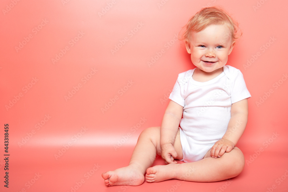 portrait caucasian curly blond smiling baby girl sitting on pink background wearing in white t-shirt. copy space. portrait caucasian curly blond smiling baby girl sitting on pink background wearing in white t-shirt. copy space.