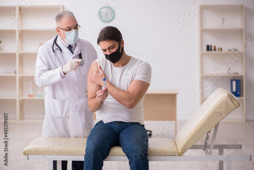 Young male patient visiting old doctor in vaccination concept