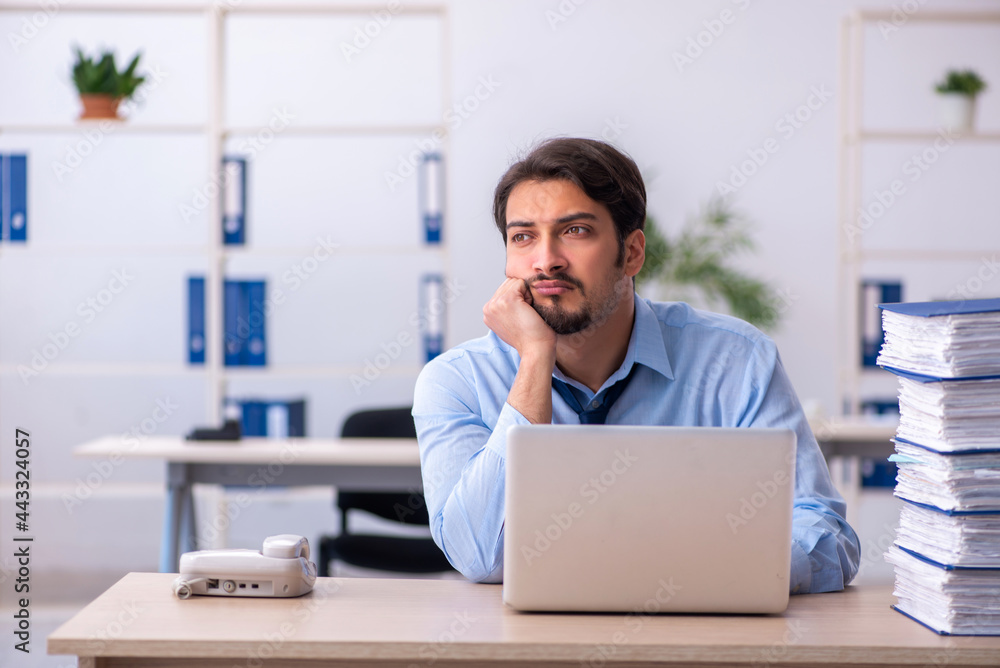 Young male employee and too much work in the office Young male employee and too much work in the office