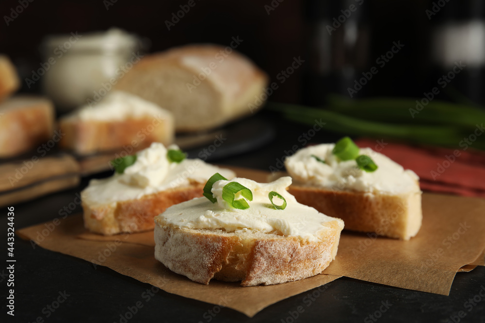 Bread with cream cheese and green onion on black table