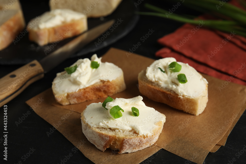 Bread with cream cheese and green onion on black table Bread with cream cheese and green onion on black table