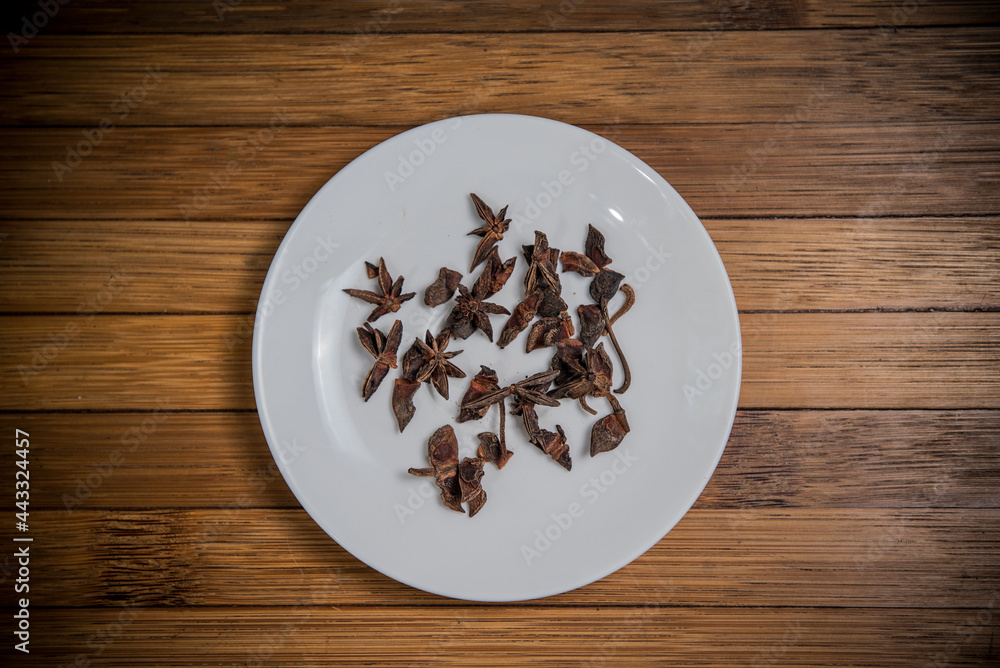 Dry Star Anise on white plate, wood background, ingredient seasoning herb vegetable