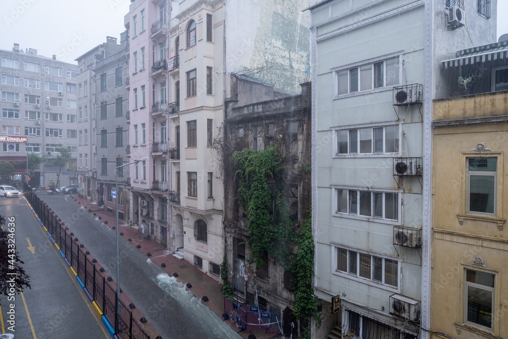 one of Taksim's street with a lot of buildings during heavy rainfall and flooding on road in city in a cloudy day climate summer rain concept