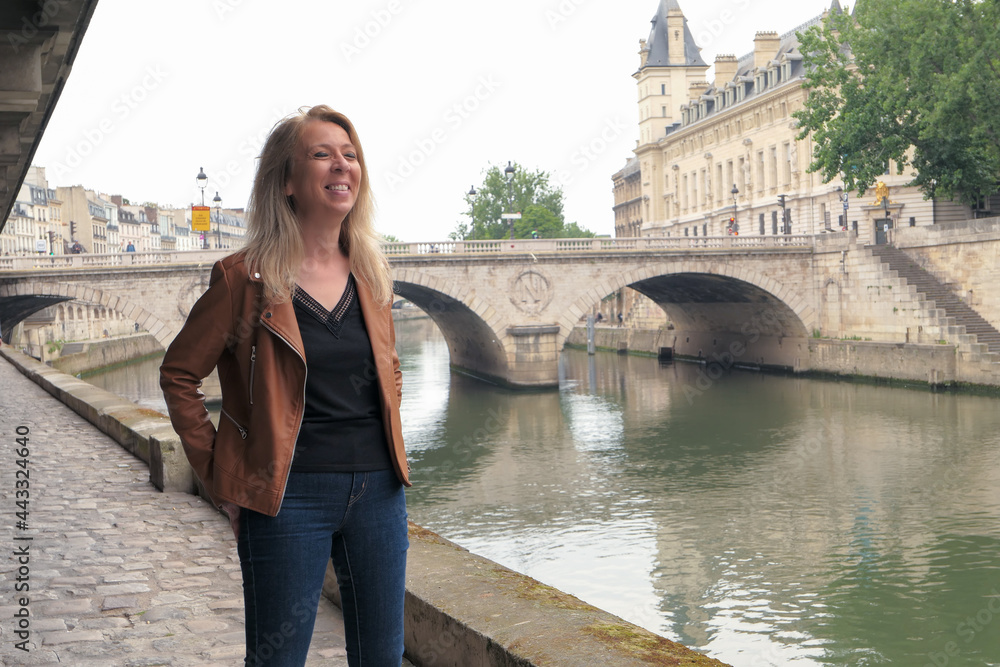 Attractive woman laughing in the city. Seine river and historic bridge in the background.