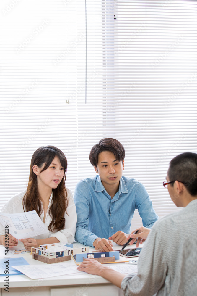 住宅模型を見ながら打ち合わせする施主と設計師 住宅模型を見ながら打ち合わせする施主と設計師