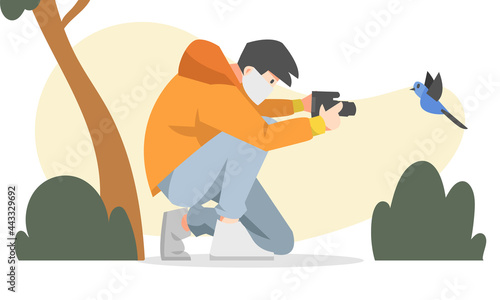 a male photographer with a mask holding a camera and taking pictures of bird. flat vector illustration with tree and plants background. for the theme of hobbies, photography and others
