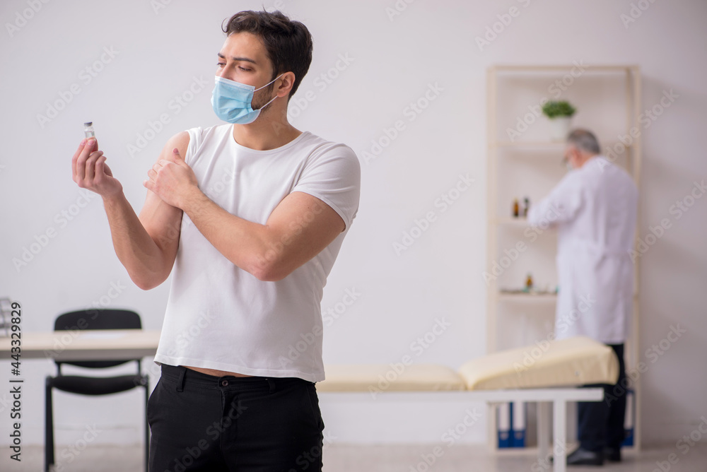 Obraz premium Young male patient visiting old male doctor in vaccination conce