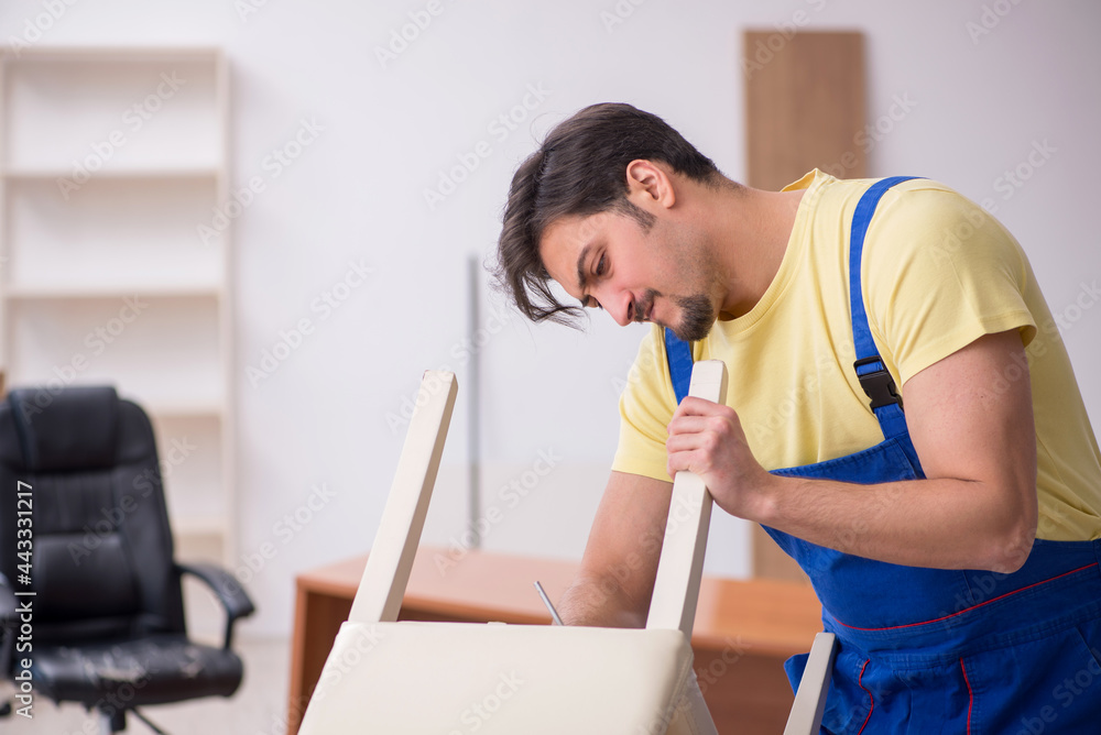 Young male carpenter repairing chair in the office