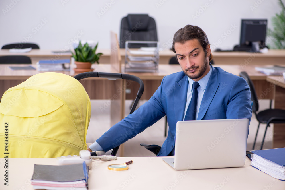 Young male employee looking after new born at workplace Young male employee looking after new born at workplace