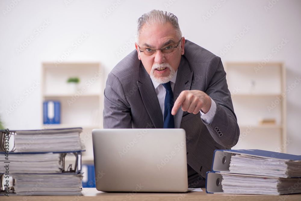 Old male employee unhappy with excessive work in the office Old male employee unhappy with excessive work in the office