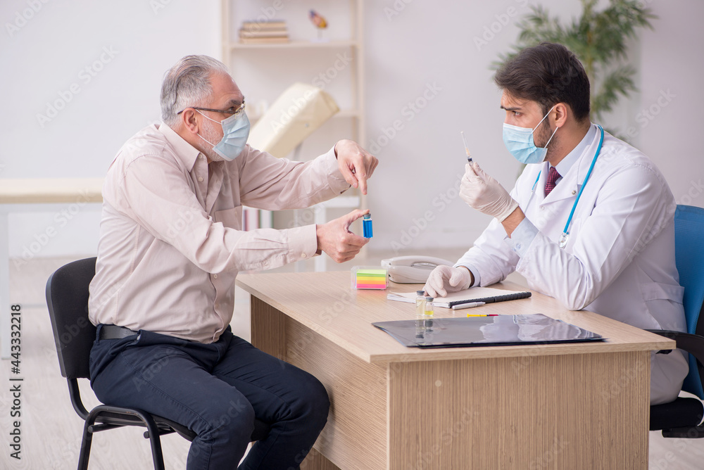 Fototapeta premium Old male patient visiting young male doctor in vaccination conce