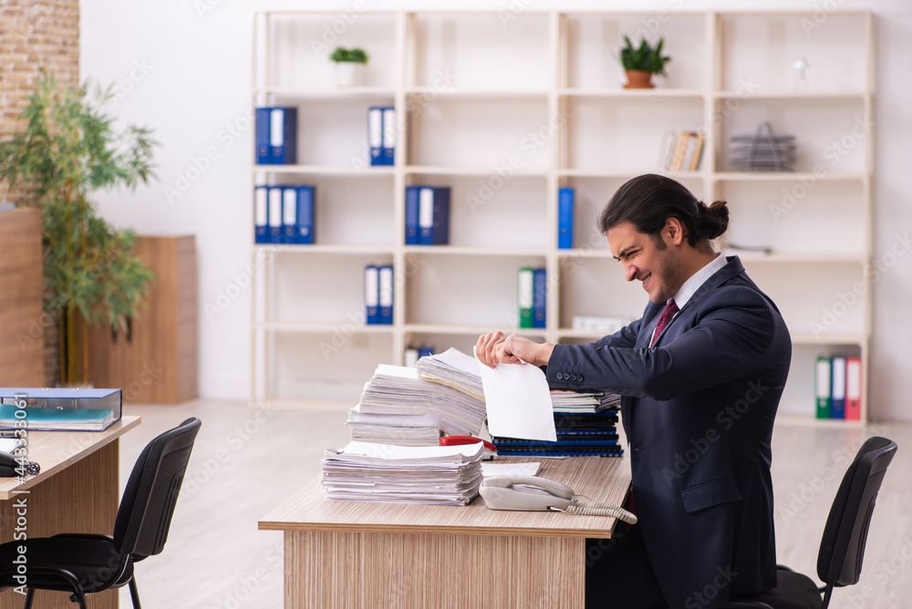 Young male employee unhappy with excessive work Young male employee unhappy with excessive work