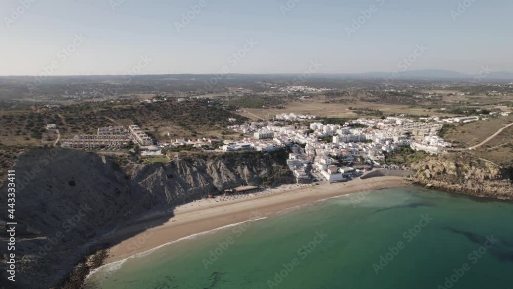 Burgau Beach surrounded by rocky cliffs, calm emerald Atlantic ocean. Aerial establisher Burgau Beach surrounded by rocky cliffs, calm emerald Atlantic ocean. Aerial establisher